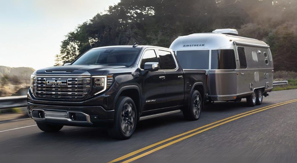 A black 2024 GMC Sierra 1500 Denali is shown towing an Airstream.