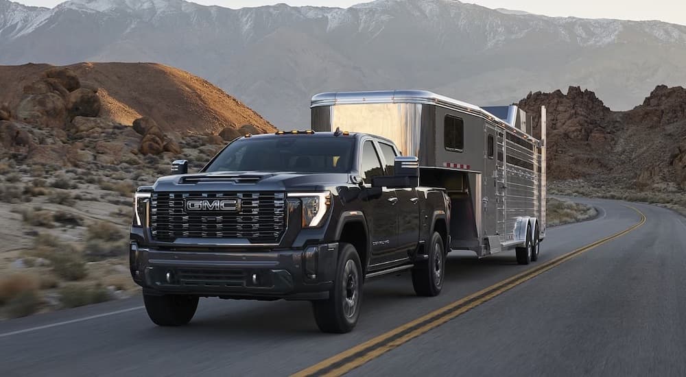 A black 2024 GMC Sierra 2500 HD is shown towing a trailer.