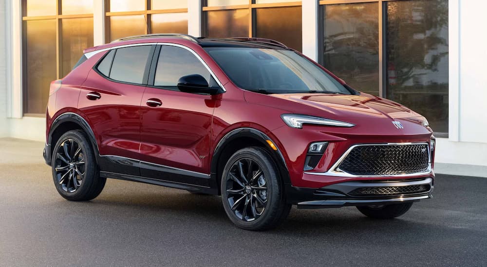 A red 2025 Buick Encore GX parked outside a Buick dealer in Lansing and angled right.