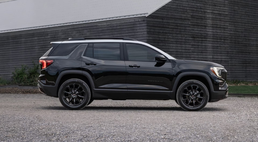 A black 2025 GMC Terrain Elevation is parked near a barn.