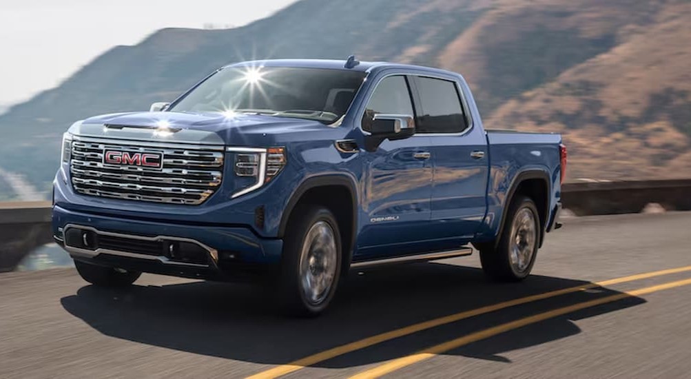 A blue 2025 GMC Sierra 1500 for sale driving on a highway.