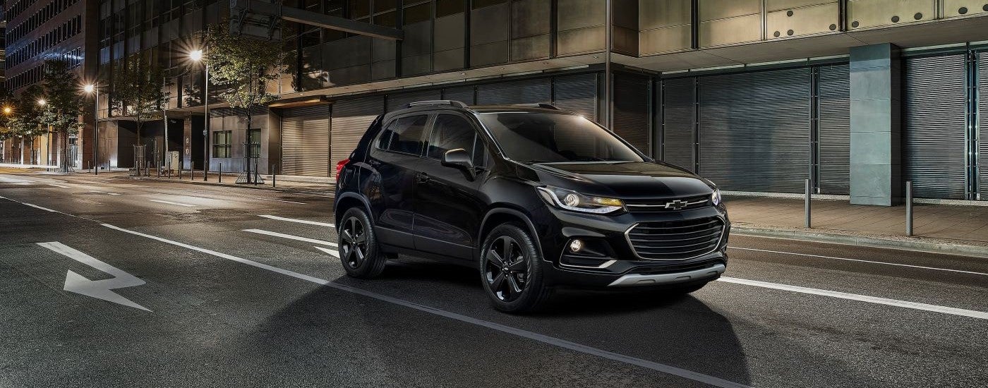 Black 2018 Chevy Trax parked by a curb in a city.