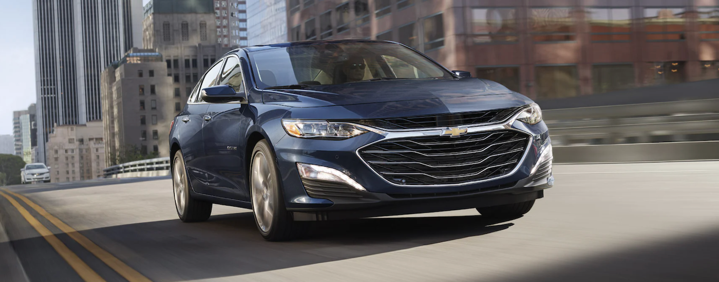 Blue 2022 Chevy Malibu driving down a city street.