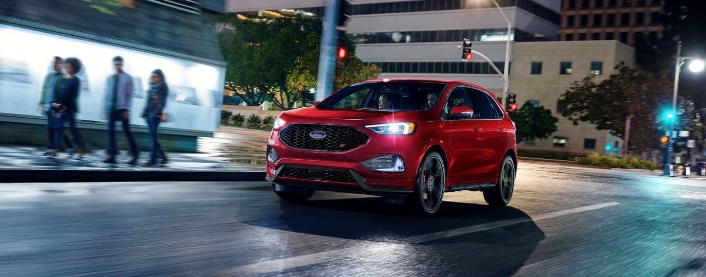 Red 2023 Ford Edge driving down a city street.
