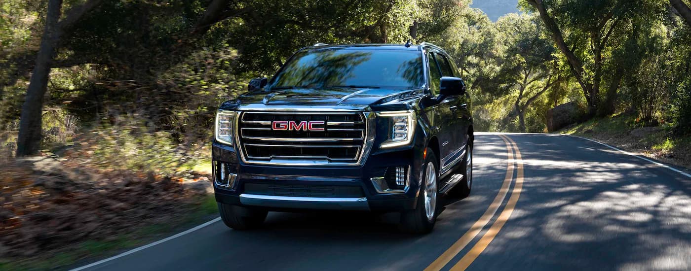 Black 2023 GMC Yukon driving down a rural road