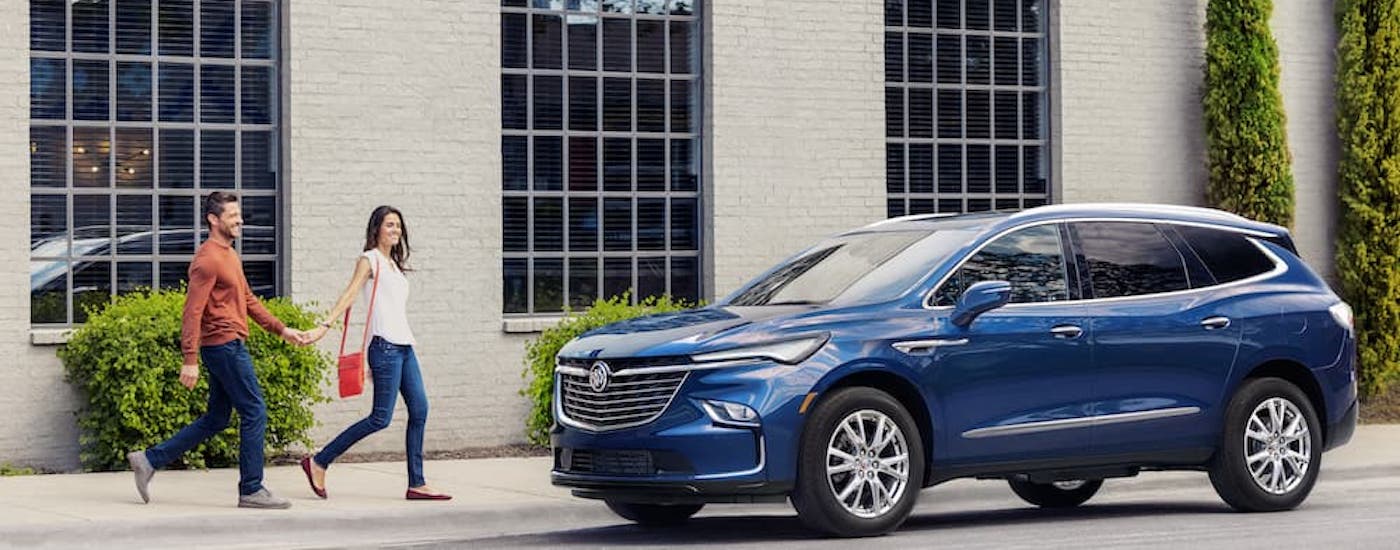 A blue 2024 Buick Enclave is shown parked in a driveway after leaving a Buick dealer.