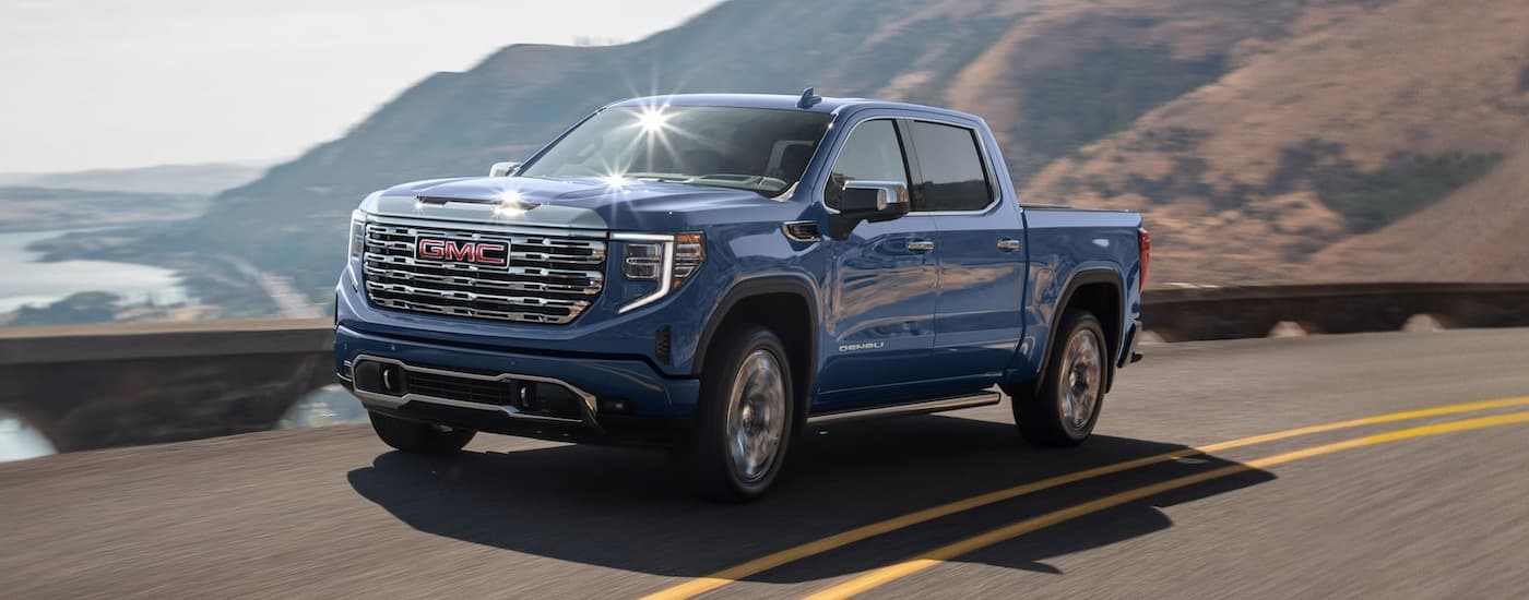 Blue 2025 GMC Sierra 1500 driving on a winding mountain road