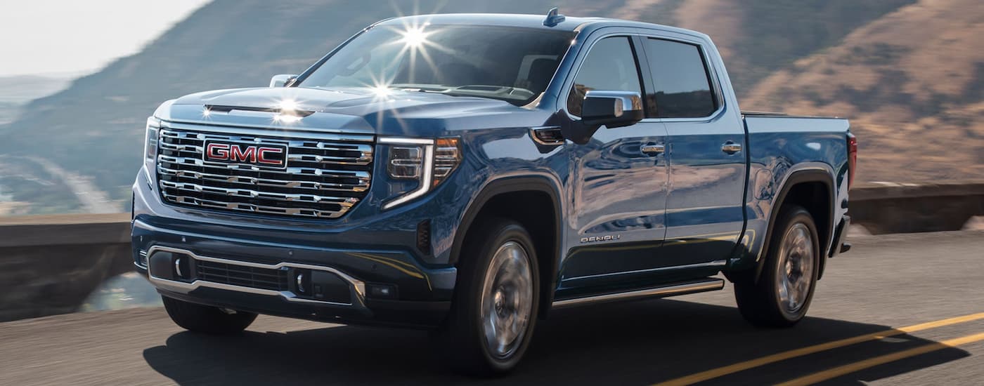Blue 2026 GMC Sierra 1500 driving down an open road.