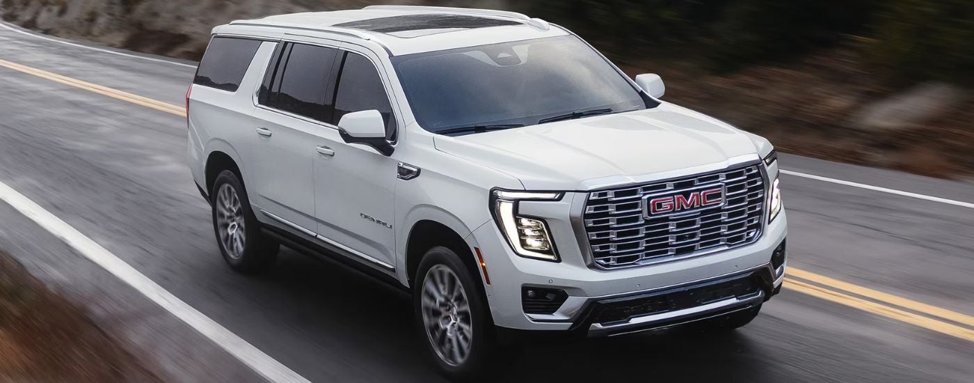 White 2026 GMC Yukon Denali driving on the road.