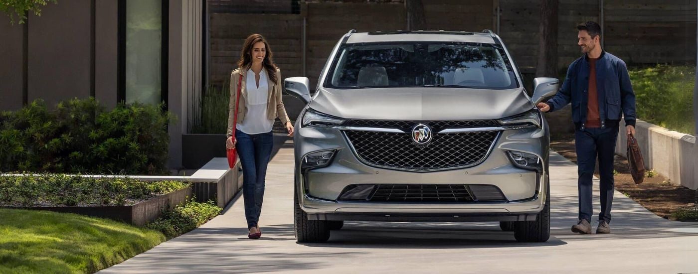 Two people walking by a grey 2024 Buick Enclave.