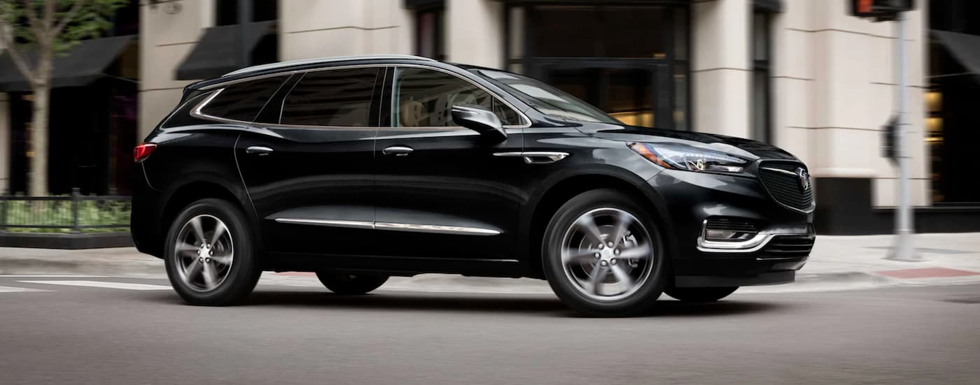 A black 2021 Buick Enclave driving through a city from a Buick dealer near Haslett.