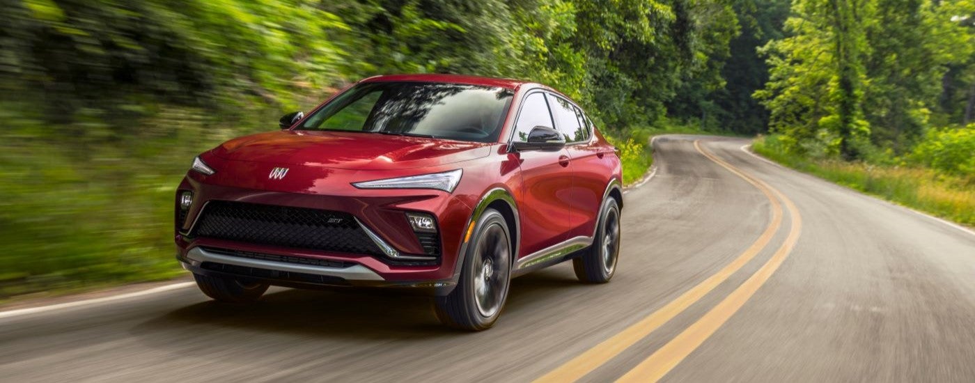A red 2024 Buick Envista ST driving around a bend from a Buick dealer near Perry.