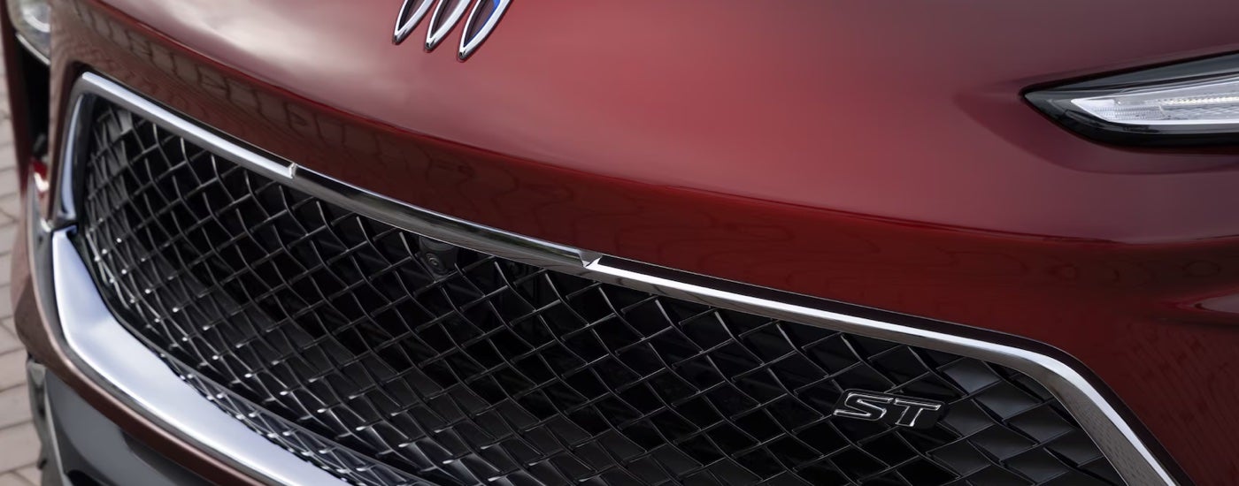 Close-up of the grille on a red 2024 Buick Encore GX ST at a Buick dealer in Lansing.