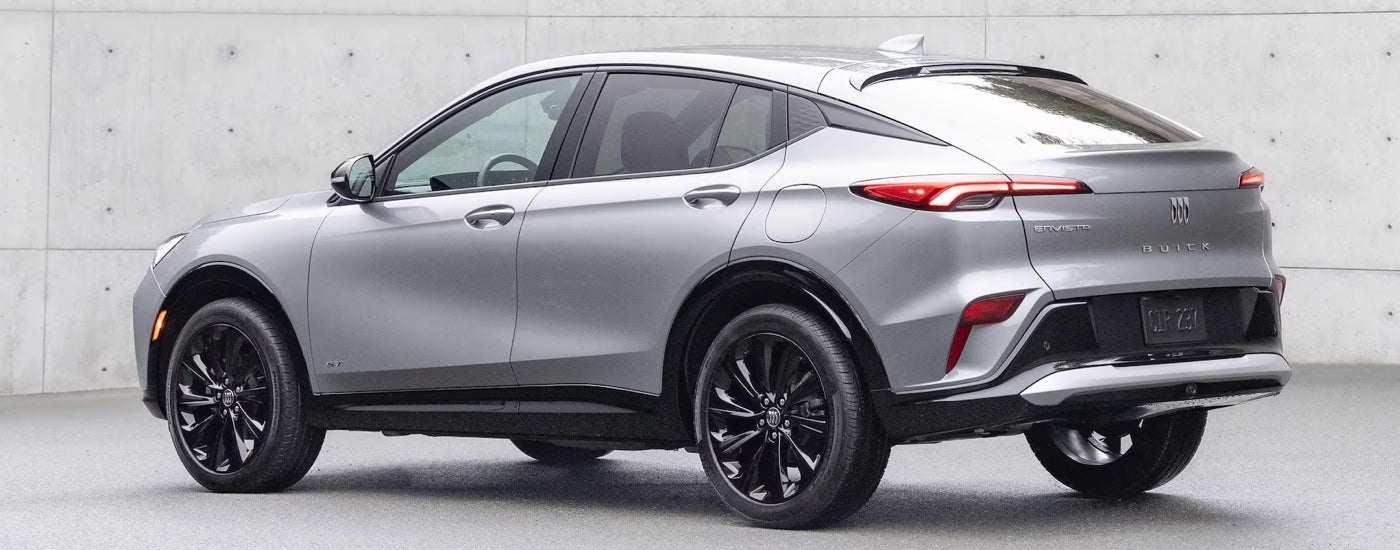 Rear view of a silver 2025 Buick Envista ST parked by a concrete wall.