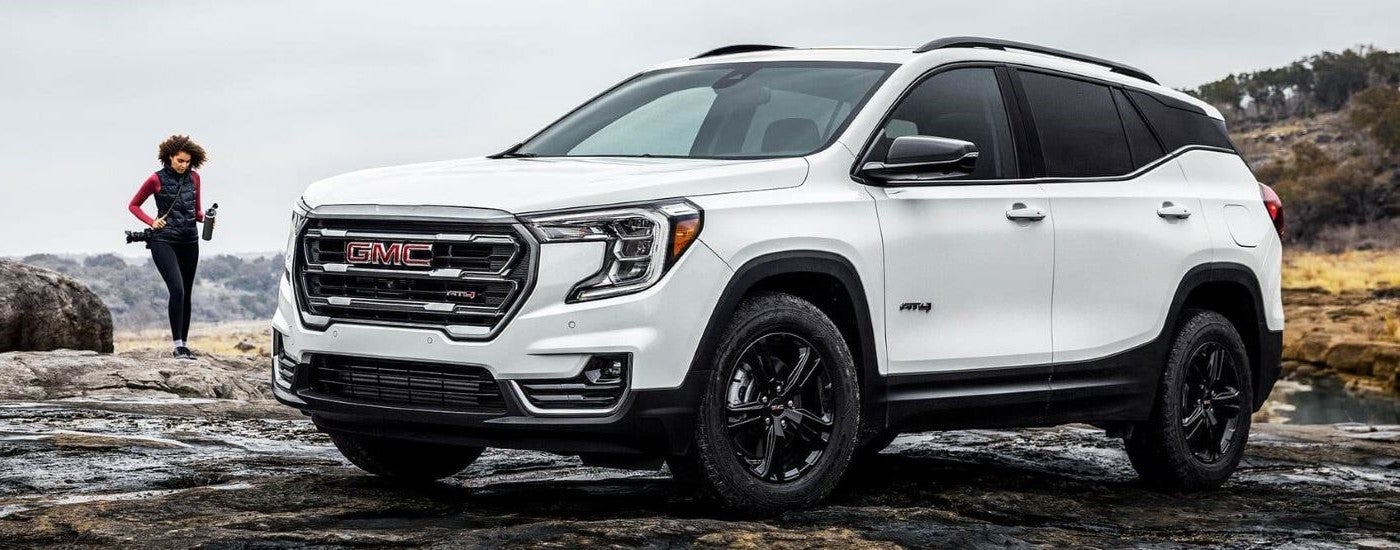 A white 2024 GMC Terrain AT4 parked off-road after visiting a GMC dealer in Lansing.
