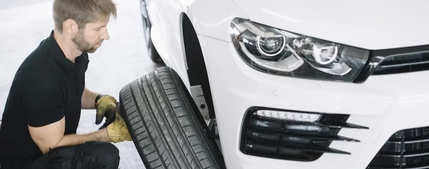 Close-up on a mechanic installing a tire on a white car.