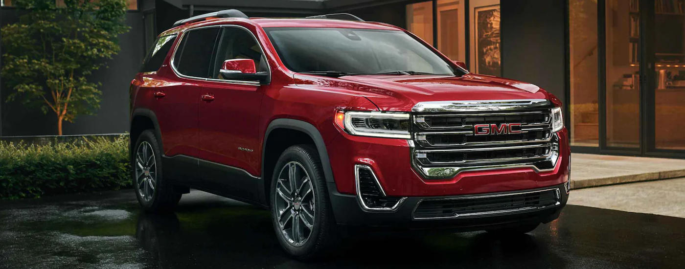 A red 2022 GMC Acadia angled right and parked on a driveway.