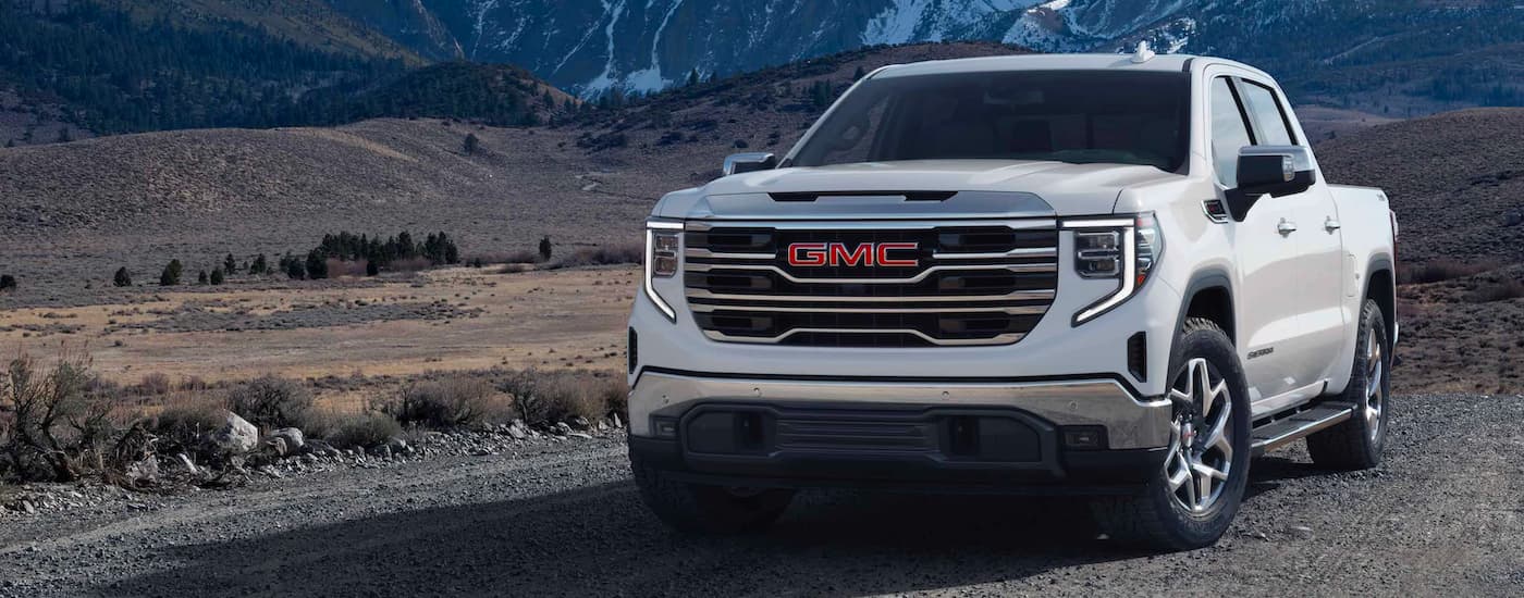 A white 2023 GMC Sierra 1500 parked off-road after visiting a used GMC dealer.