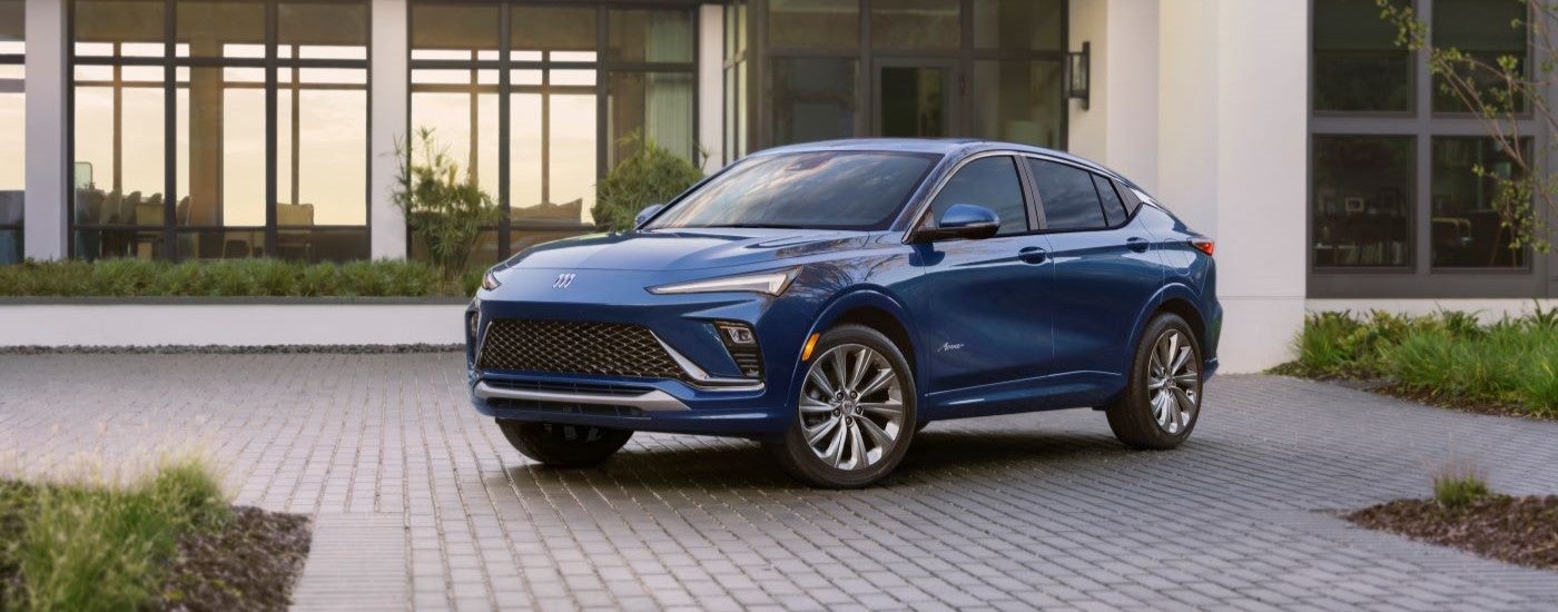 A blue 2024 Buick Enclave Avenir is shown parked in a driveway.