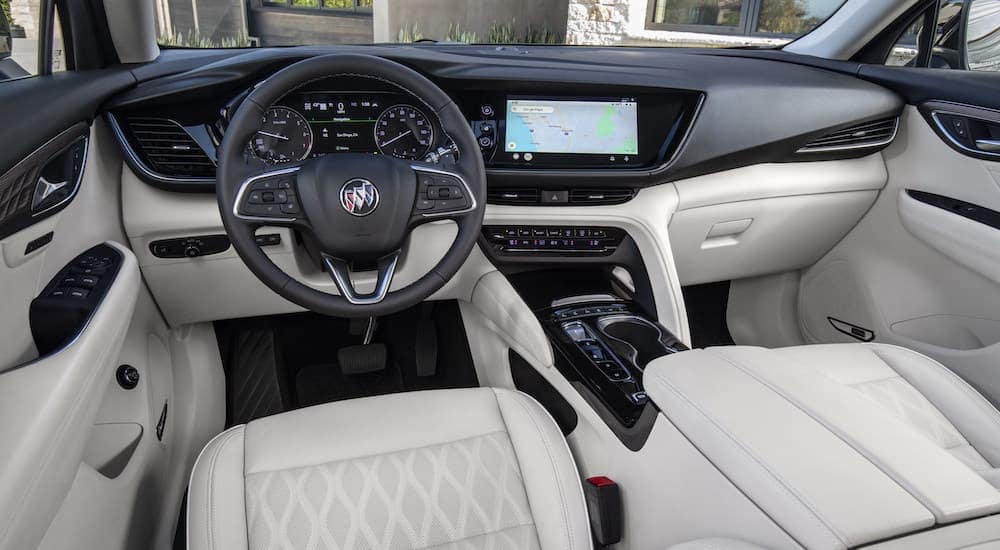 The steering wheel and dash in the black and white interior of a 2023 Buick Envision.